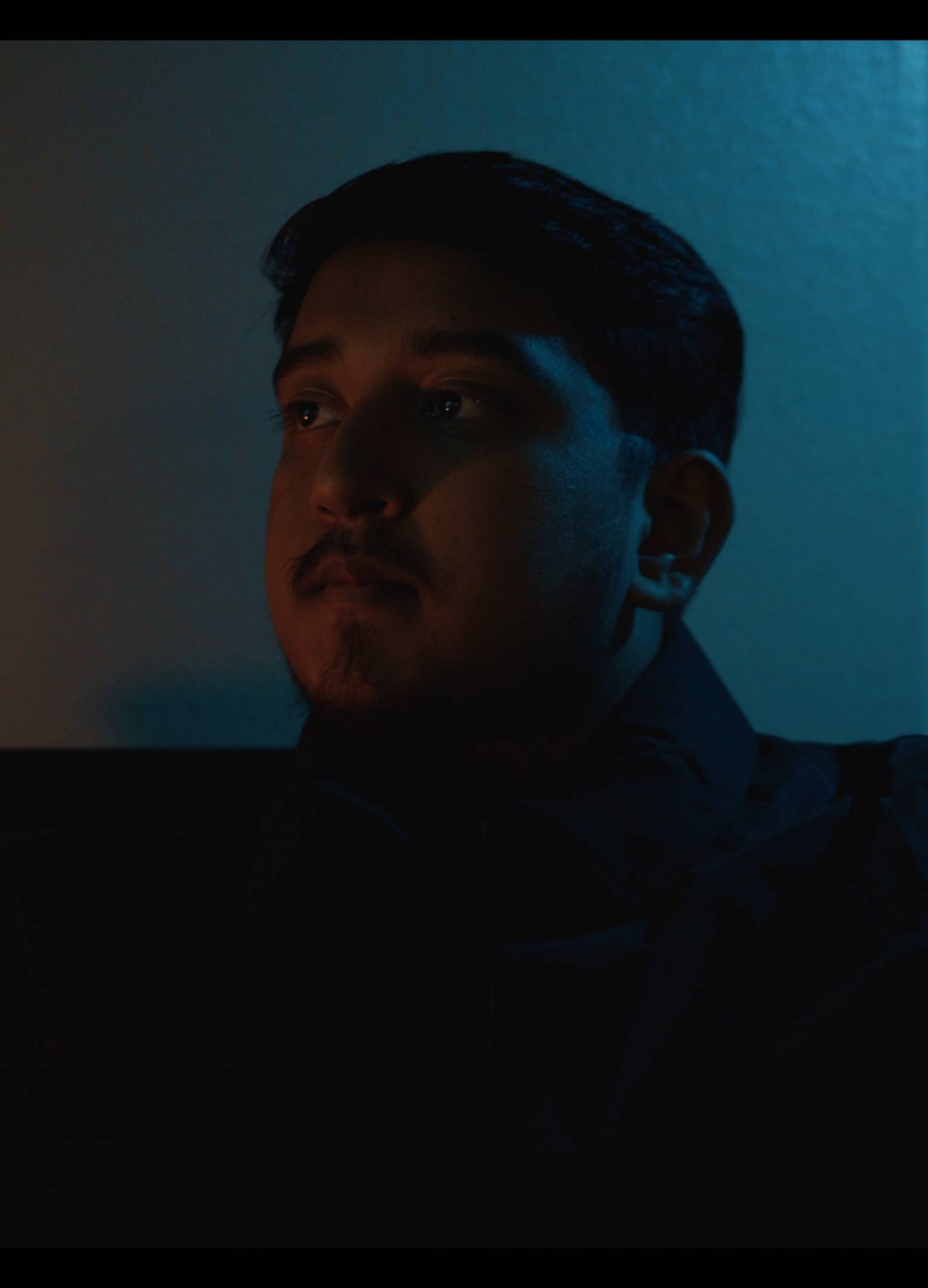 Moody split-lit portrait of Yafi in orange and teal light